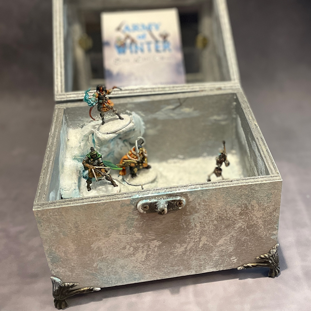 Decorative wood and Glass-topped display case containing diorama of handpainted miniatures for Army of Winter RPG one-shot, of which, the box is being displayed as well